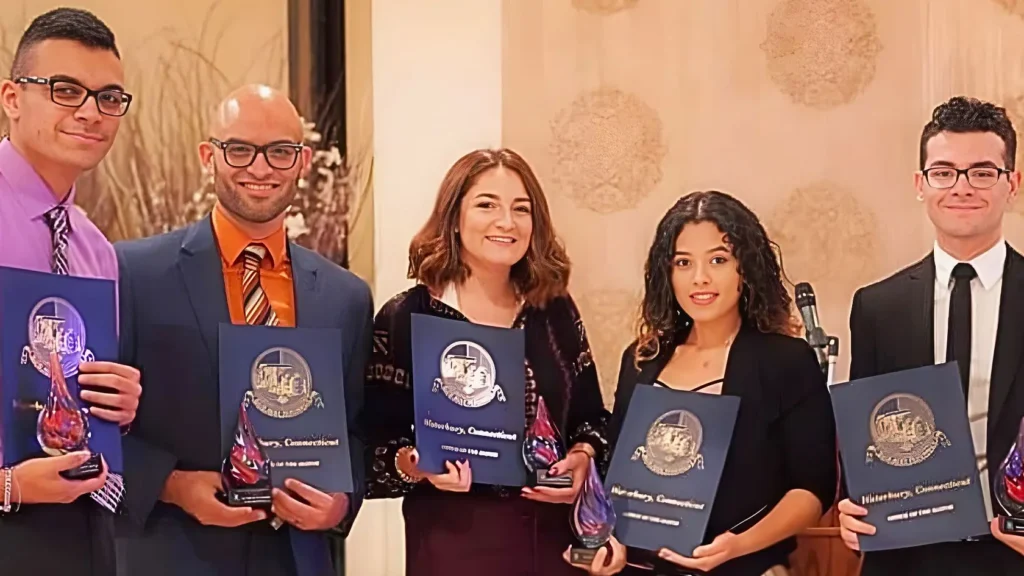 Five people holding award plaques, smiling.